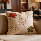 Beige pillow embroidered with red, gold and green maple leaves on a cream chair