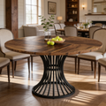 Plank top round table on a black spoke pedestal with a fruit bowl by an open kitchen
