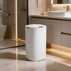 White sensor trash can beside a floating vanity in a softly lit bathroom