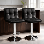Two black tufted bar stools with chrome bases pulled up to a pale kitchen island