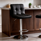 Close view of a single black tufted stool with its chrome footrest at a kitchen island