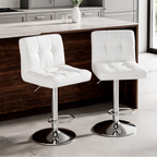 Two white tufted counter stools with round chrome bases at a dark wood island