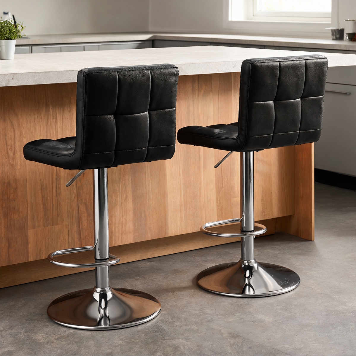 Black leather look stools side by side at a wooden island with daylight from a window
