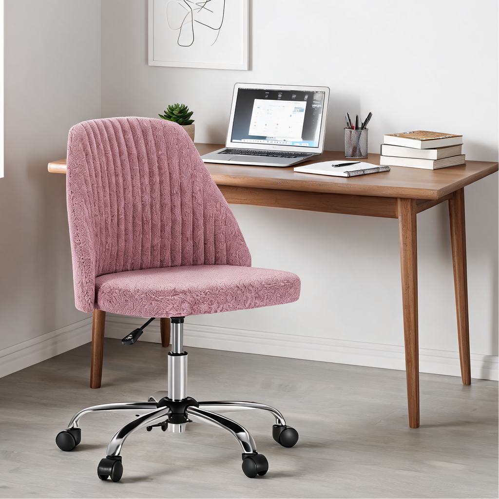 Pink armless chair at a wooden desk with a laptop, books and a potted plant