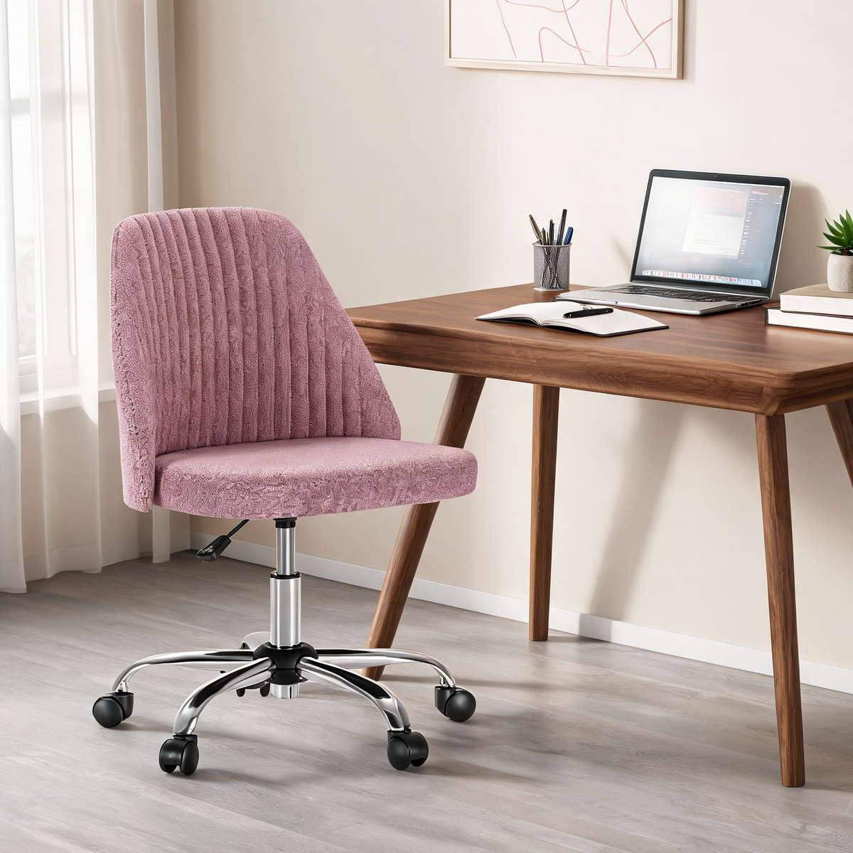 Pink armless task chair on casters beside a wooden desk with a laptop and pencil cup