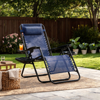 Navy reclining lounge chair on an outdoor rug with a drink on the tray and flowerbeds behind