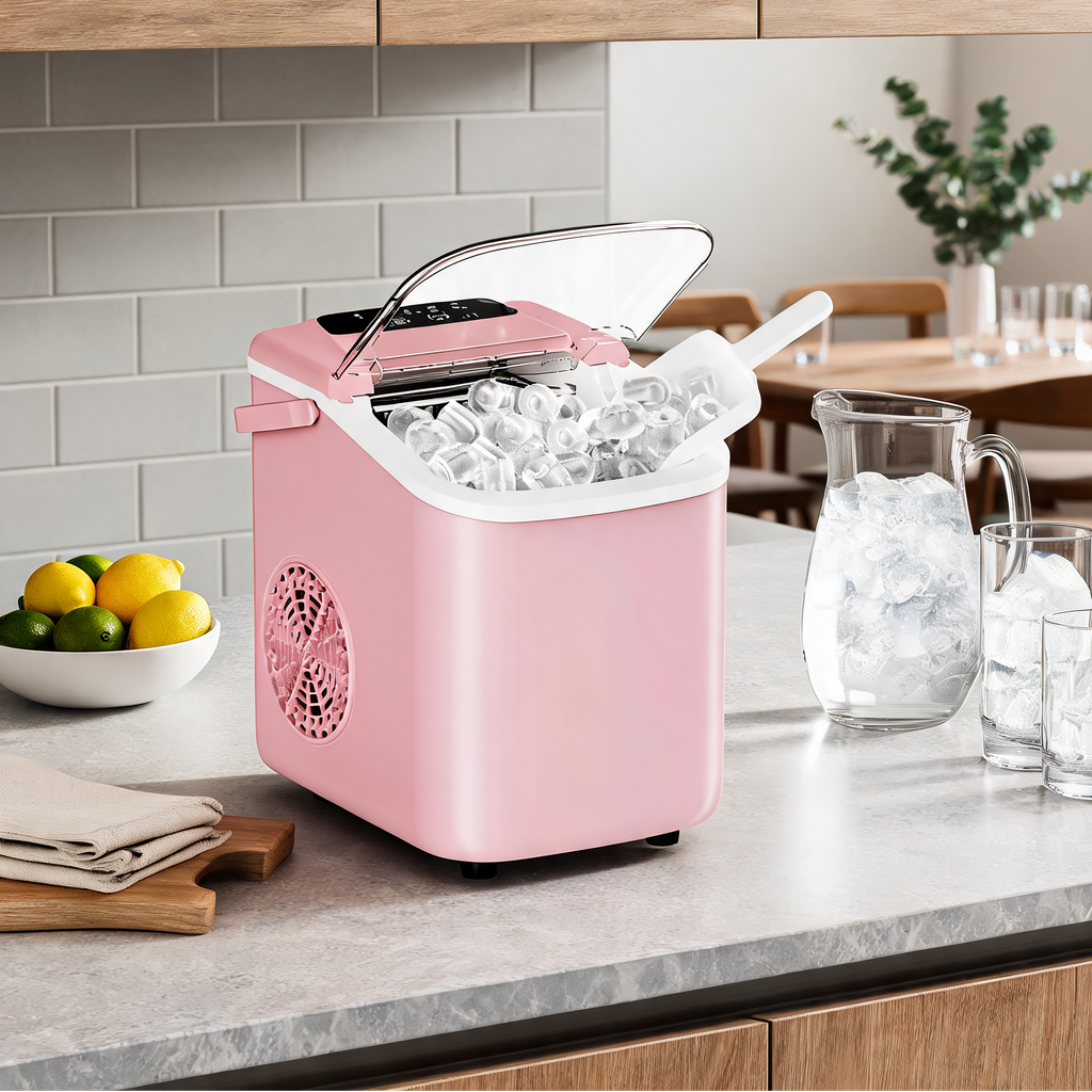 Pink countertop ice machine holding ice, with a pitcher of ice cubes and two glasses on a kitchen counter