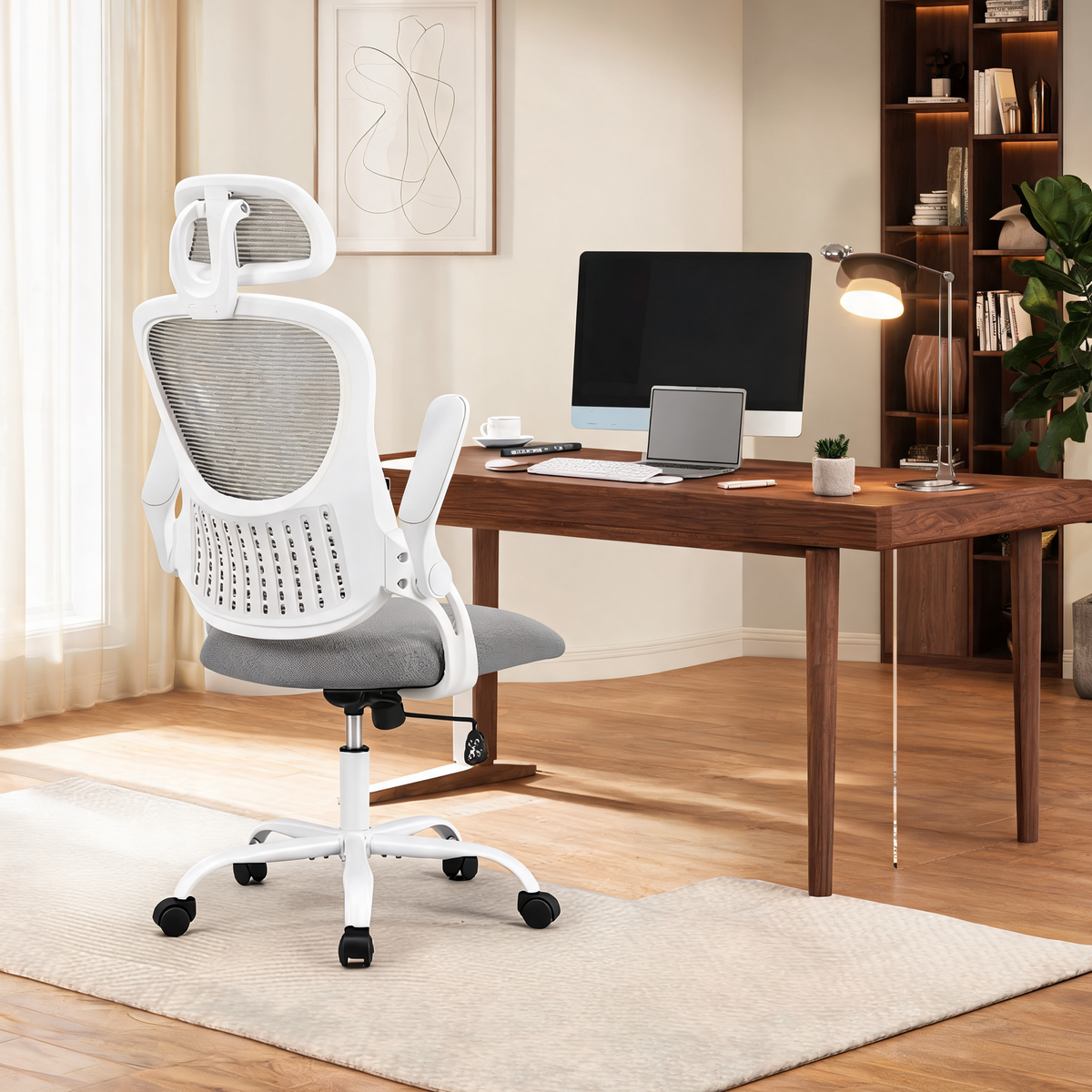 Gray mesh chair with a headrest pulled up to a wide wooden table with a monitor