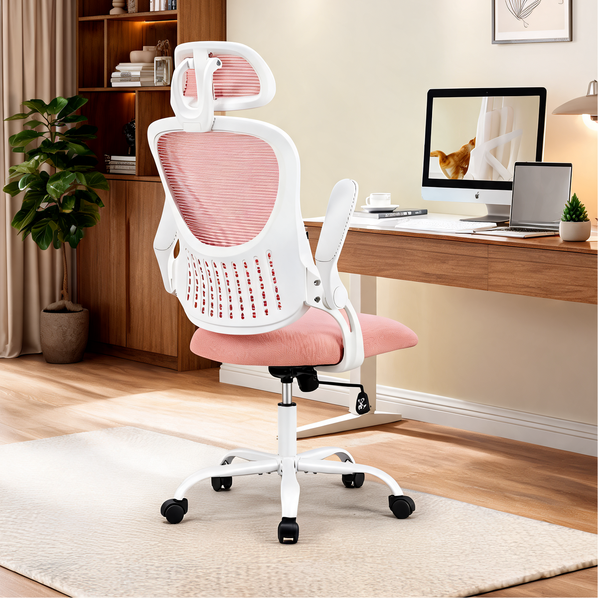 Pink mesh chair with a white frame at a wooden desk holding a monitor and a small plant