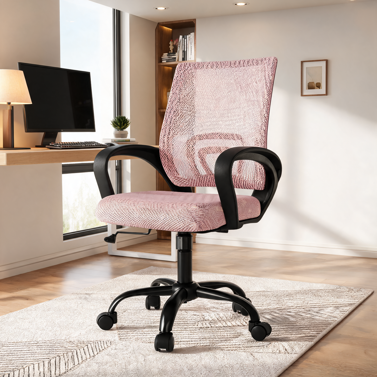 Pink mesh back office chair in a bright office with a monitor and framed art