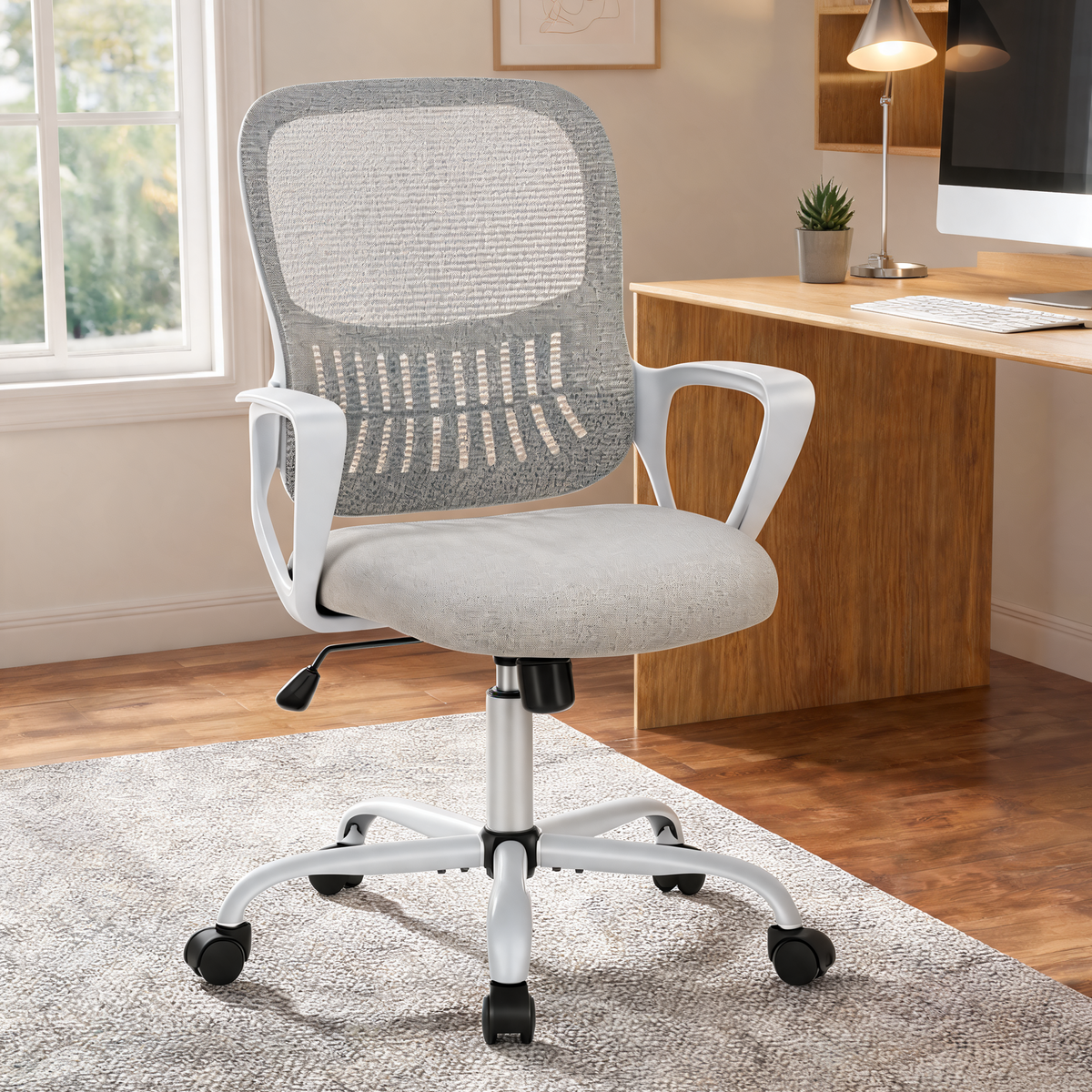 Gray mesh back office chair with white frame and loop arms beside a wooden home office desk