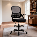 Black mesh drafting chair with a footring shown alone on a rug in an empty bright room