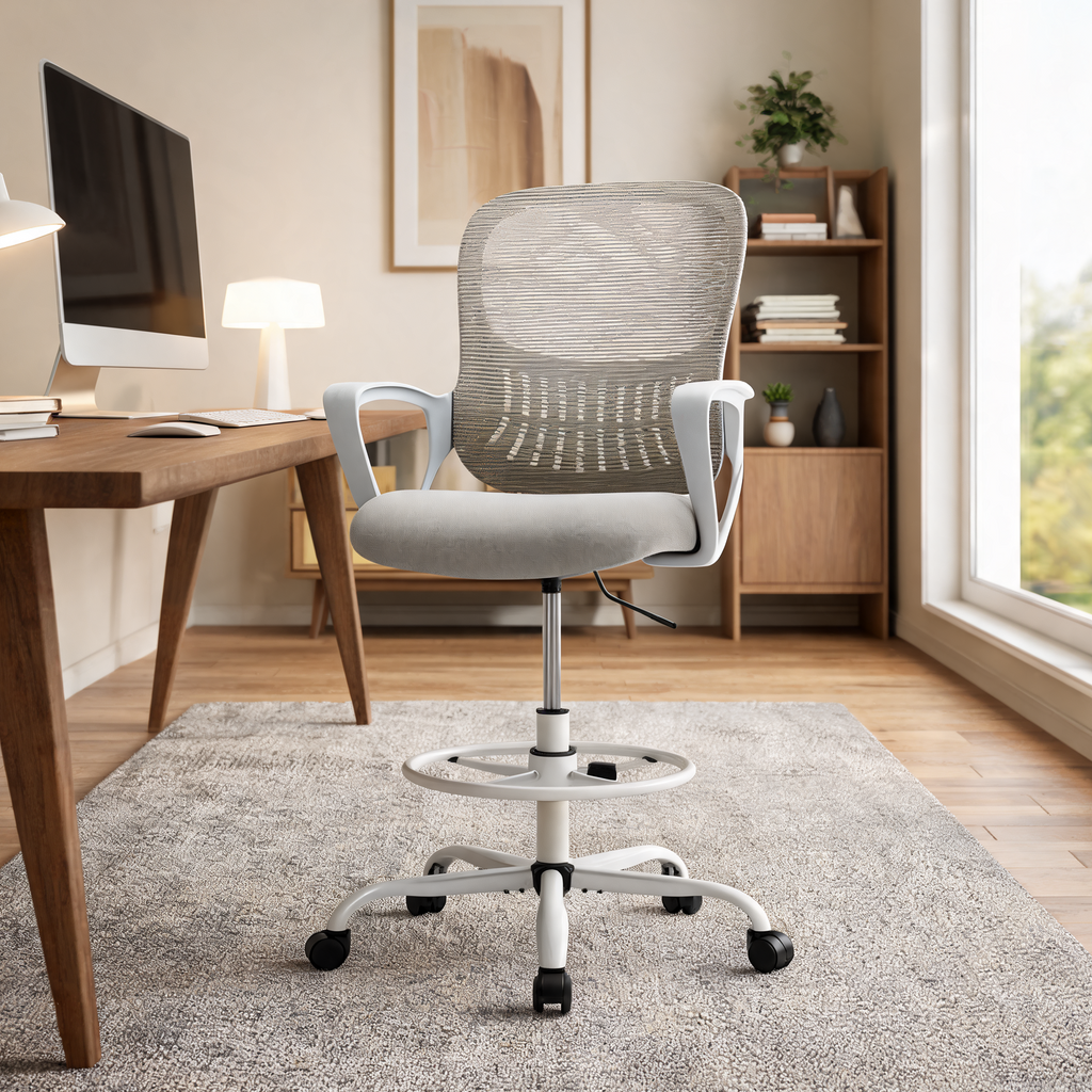 Gray drafting chair with a chrome footring beside a wooden desk with shelves and a plant