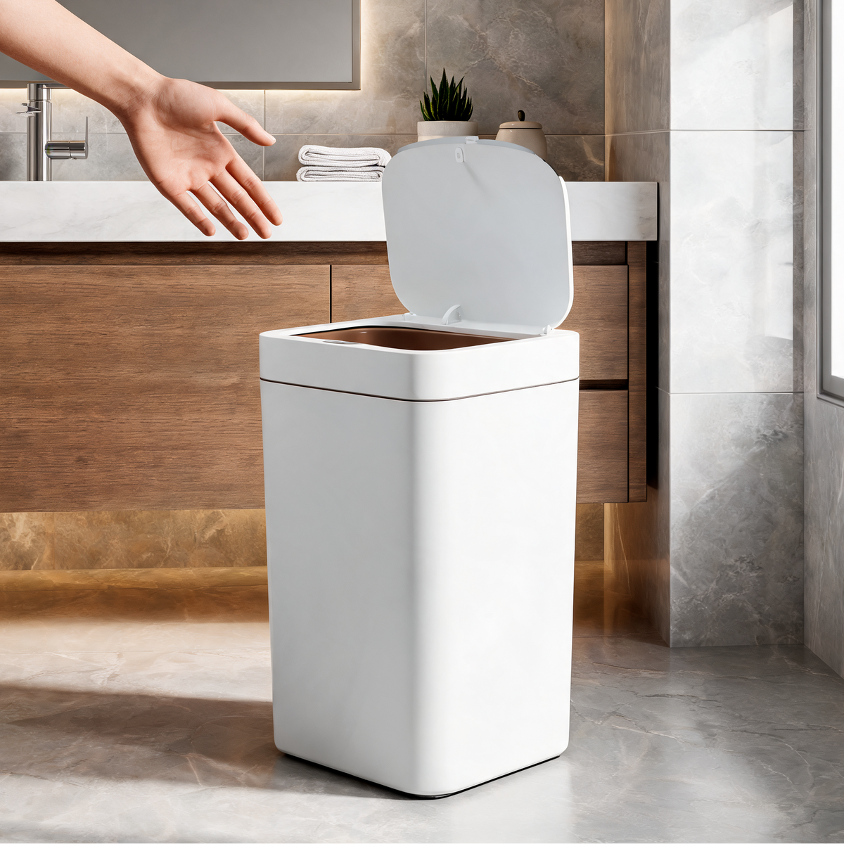 Hand reaching toward the open sensor trash can beside a stone bathroom counter