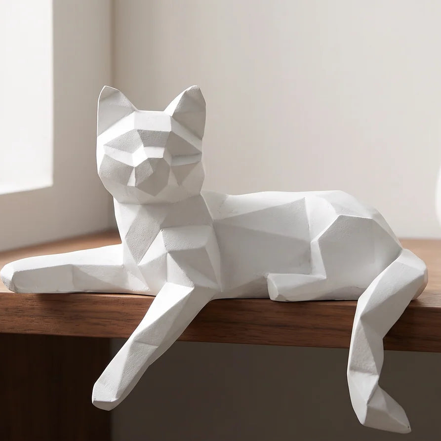 White faceted cat figurine lying along a wood shelf edge with one paw hanging